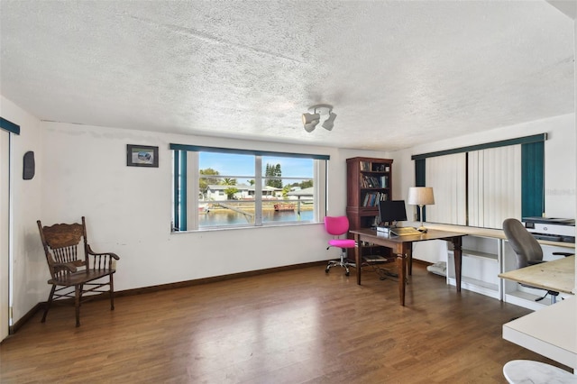 office area with a textured ceiling, baseboards, and wood finished floors