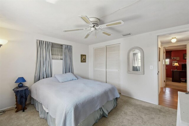 bedroom with a ceiling fan, visible vents, a closet, and light colored carpet