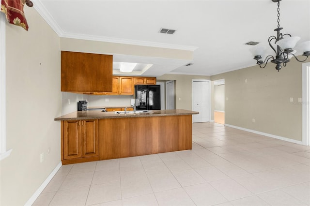 kitchen featuring visible vents, a sink, a peninsula, brown cabinetry, and black refrigerator with ice dispenser