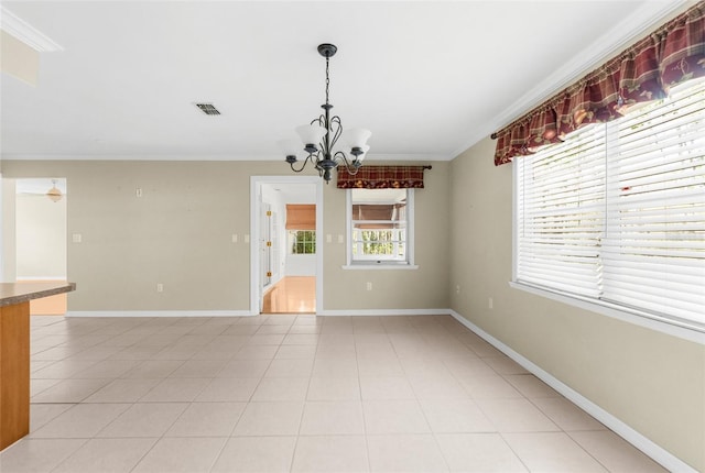 empty room with light tile patterned floors, visible vents, an inviting chandelier, and crown molding