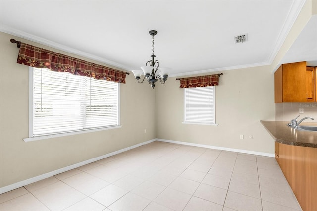 unfurnished dining area with visible vents, crown molding, baseboards, a chandelier, and a sink