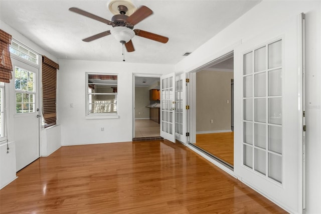 interior space with visible vents, french doors, a ceiling fan, and wood finished floors