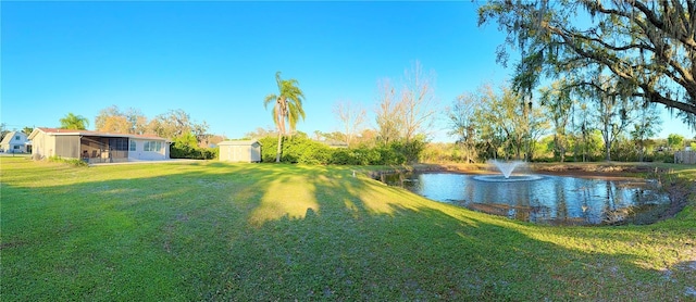 view of yard with an outbuilding, a water view, and a shed