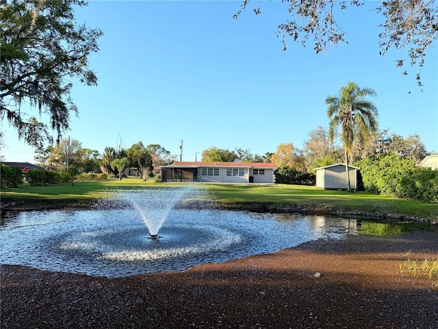 surrounding community with a water view, an outdoor structure, and a yard