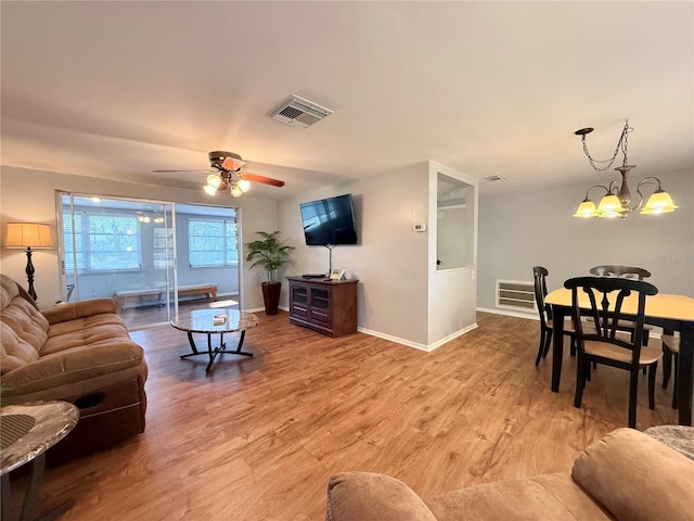 living room with light wood-style floors, visible vents, baseboards, and ceiling fan with notable chandelier