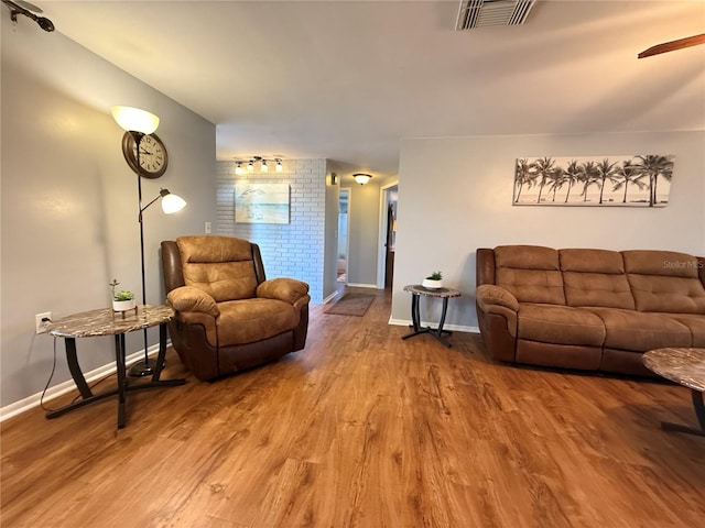 living area with visible vents, baseboards, and wood finished floors