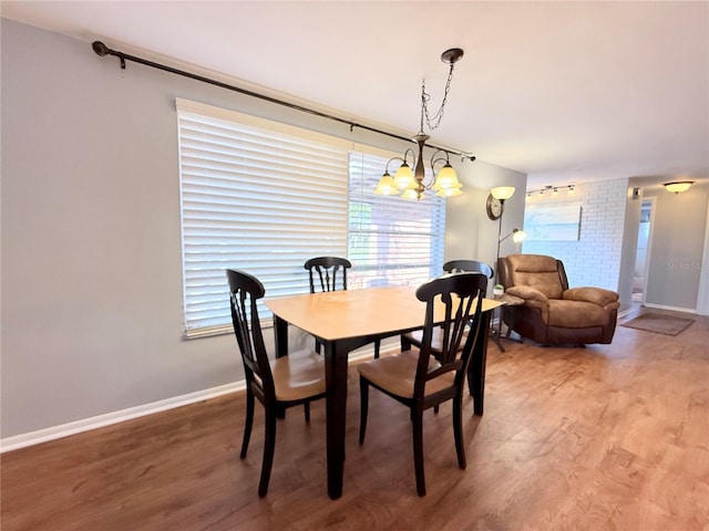 dining space featuring light wood-style floors, baseboards, and a notable chandelier