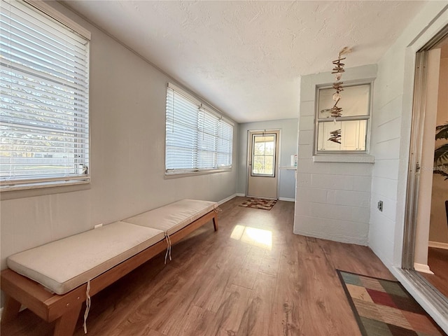 doorway featuring light wood-style floors, a textured ceiling, and baseboards
