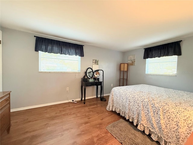 bedroom with multiple windows, baseboards, and wood finished floors