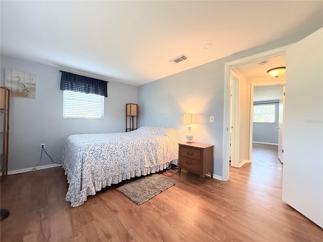 bedroom featuring visible vents, baseboards, and wood finished floors