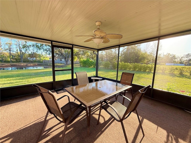 sunroom / solarium with ceiling fan and a water view