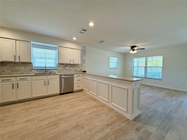 kitchen featuring visible vents, backsplash, light countertops, stainless steel dishwasher, and a sink