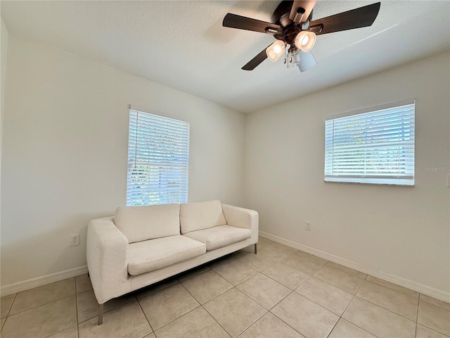 sitting room featuring light tile patterned floors, a ceiling fan, baseboards, and a textured ceiling