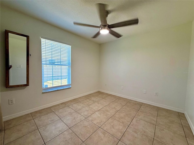 spare room with a ceiling fan, a textured ceiling, baseboards, and light tile patterned floors