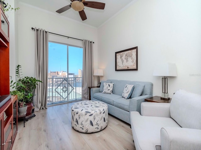 living area featuring light wood finished floors, ceiling fan, ornamental molding, and a view of city