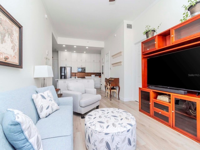 living area featuring visible vents, light wood-style flooring, and baseboards