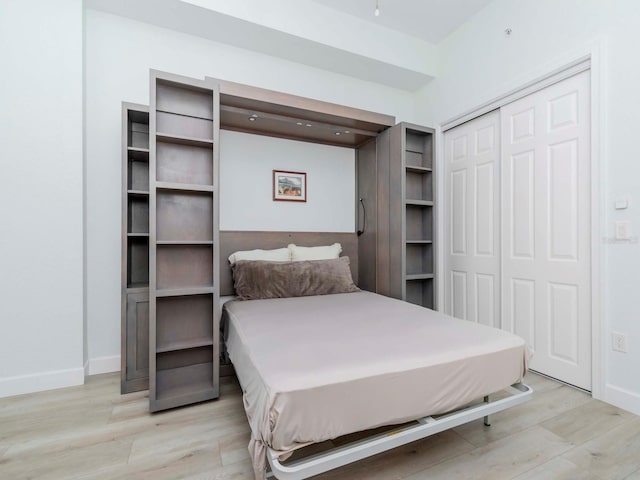 bedroom with light wood-style floors, a closet, and baseboards