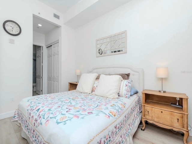 bedroom featuring a closet, visible vents, baseboards, and wood finished floors