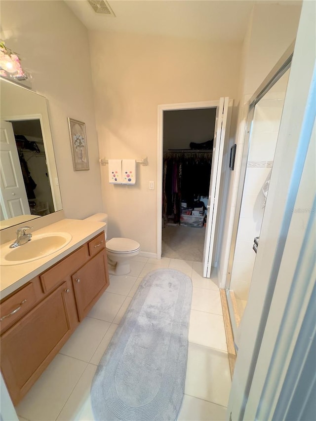 full bath with a stall shower, a walk in closet, vanity, and tile patterned floors