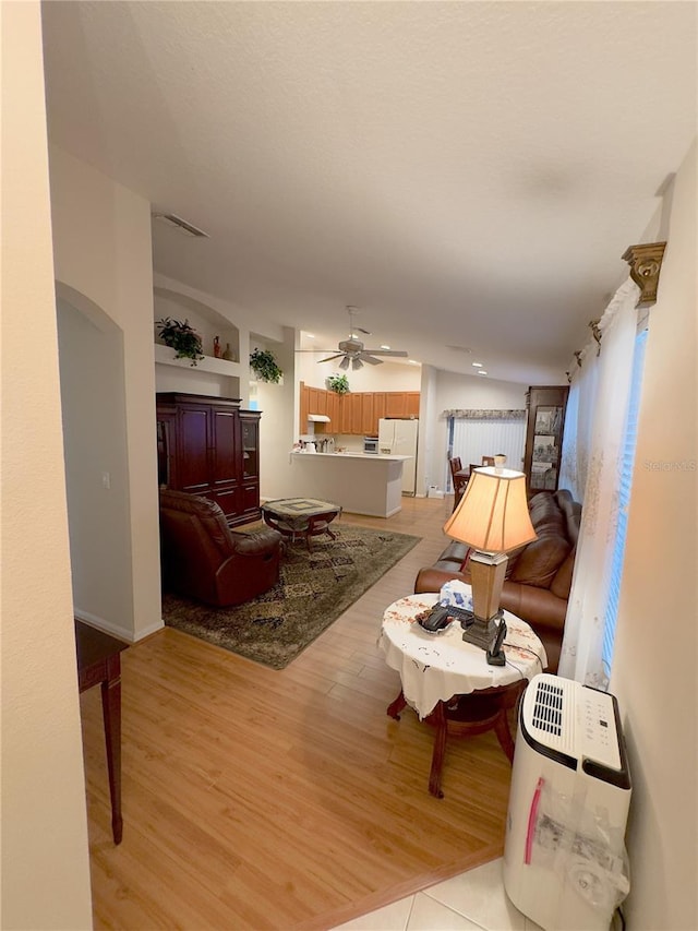 living area featuring light wood finished floors and ceiling fan