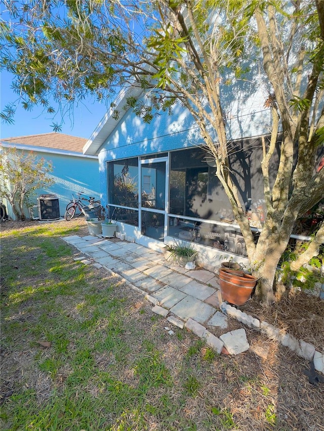 back of property with a patio area, a sunroom, and central air condition unit