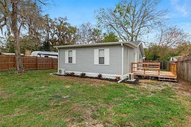 rear view of property featuring a fenced backyard, a yard, and a deck