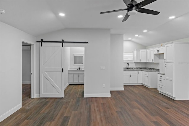 kitchen with dark wood-style floors, white cabinets, vaulted ceiling, and a barn door