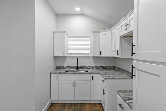 kitchen featuring lofted ceiling, dark wood-style flooring, white cabinets, and a sink