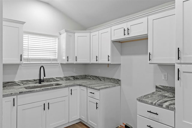 kitchen featuring lofted ceiling, white cabinetry, and a sink