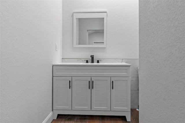 bathroom featuring a textured wall, baseboards, wood finished floors, and vanity