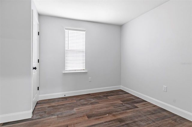 spare room featuring baseboards and dark wood-type flooring