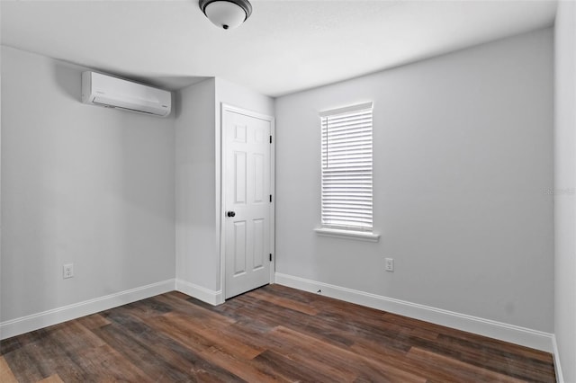 empty room with dark wood-style floors, an AC wall unit, and baseboards