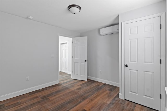 unfurnished bedroom featuring dark wood-type flooring, baseboards, and a wall mounted AC