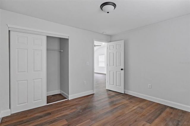 unfurnished bedroom with a closet, wood finished floors, and baseboards