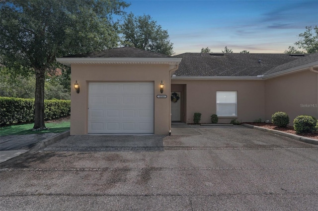 view of front facade with a garage, driveway, roof with shingles, and stucco siding