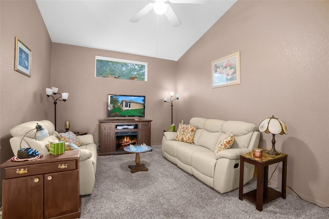 living room with a warm lit fireplace, vaulted ceiling, a ceiling fan, and light colored carpet