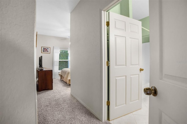 corridor featuring light tile patterned floors and light colored carpet