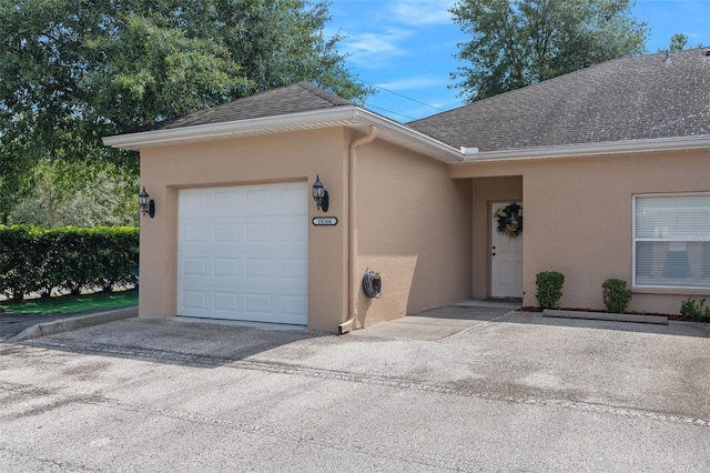 single story home with concrete driveway, a shingled roof, an attached garage, and stucco siding