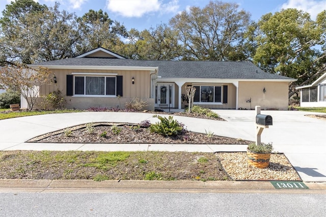 ranch-style home featuring concrete driveway, board and batten siding, and roof with shingles