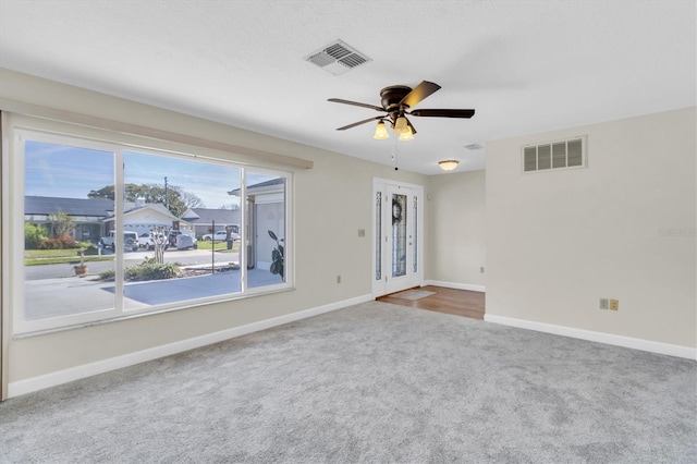 unfurnished room with carpet, visible vents, and baseboards