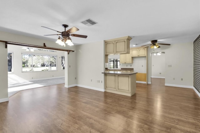 unfurnished living room featuring baseboards, dark wood-type flooring, visible vents, and a ceiling fan