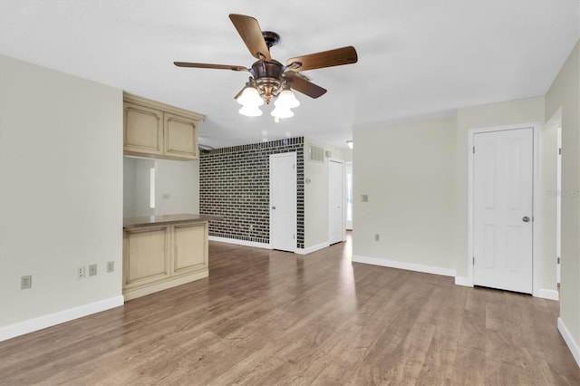 unfurnished living room with wood finished floors, a ceiling fan, and baseboards