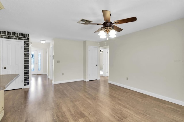 unfurnished living room featuring ceiling fan, wood finished floors, visible vents, and baseboards