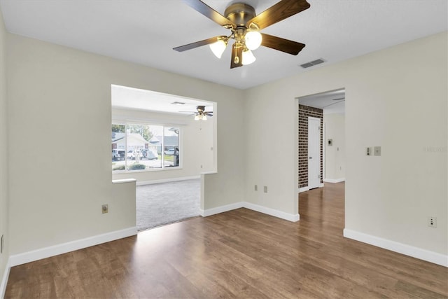 unfurnished room with visible vents, ceiling fan, baseboards, and wood finished floors