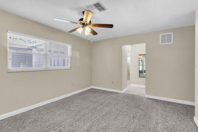 unfurnished room with a ceiling fan, visible vents, light carpet, and baseboards