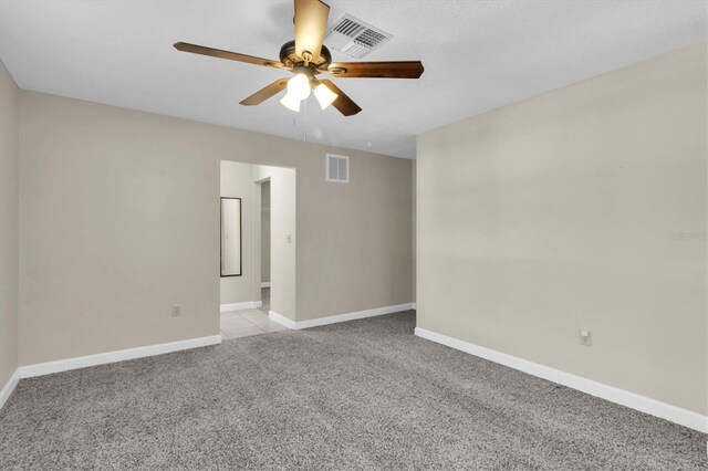 spare room with visible vents, ceiling fan, light carpet, and baseboards