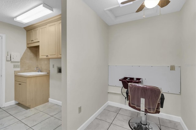 laundry area with light tile patterned floors, cabinet space, baseboards, a ceiling fan, and a sink