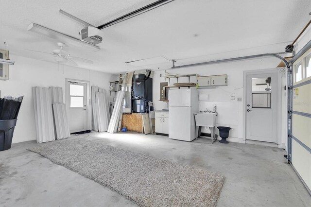 garage with a garage door opener, a sink, and freestanding refrigerator