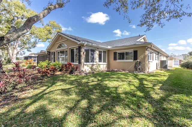 exterior space featuring a sunroom, central AC unit, a lawn, and stucco siding