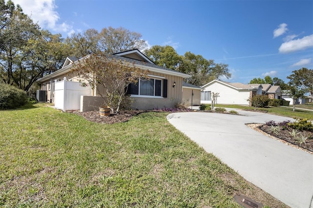 single story home with concrete driveway, central AC, and a front yard